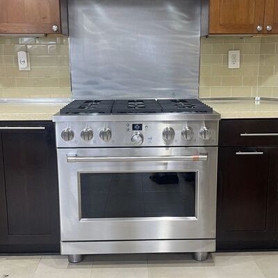 A stainless professional-style range standing between dark cabinets under a matching hood.