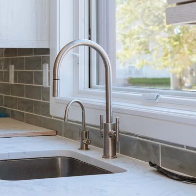 An undermount sink and a pull-down faucet at a kitchen window, the counter still masked off.