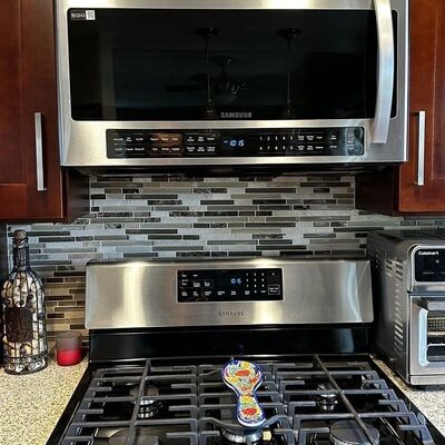 An over-the-range microwave installed above a gas range, ducted up into the cabinet.